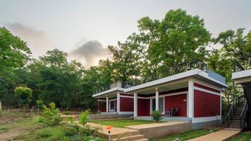 A two-story building with a red and white exterior, surrounded by lush greenery and trees.