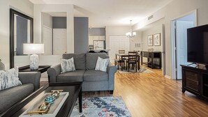 A modern living room with a grey sofa, a coffee table, and a TV stand.