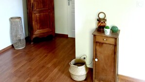 A hallway with a wooden cabinet, a wicker basket, and a small wooden cabinet with decorative items. - Le Clos Beauséjour (Mauges-sur-Loire)