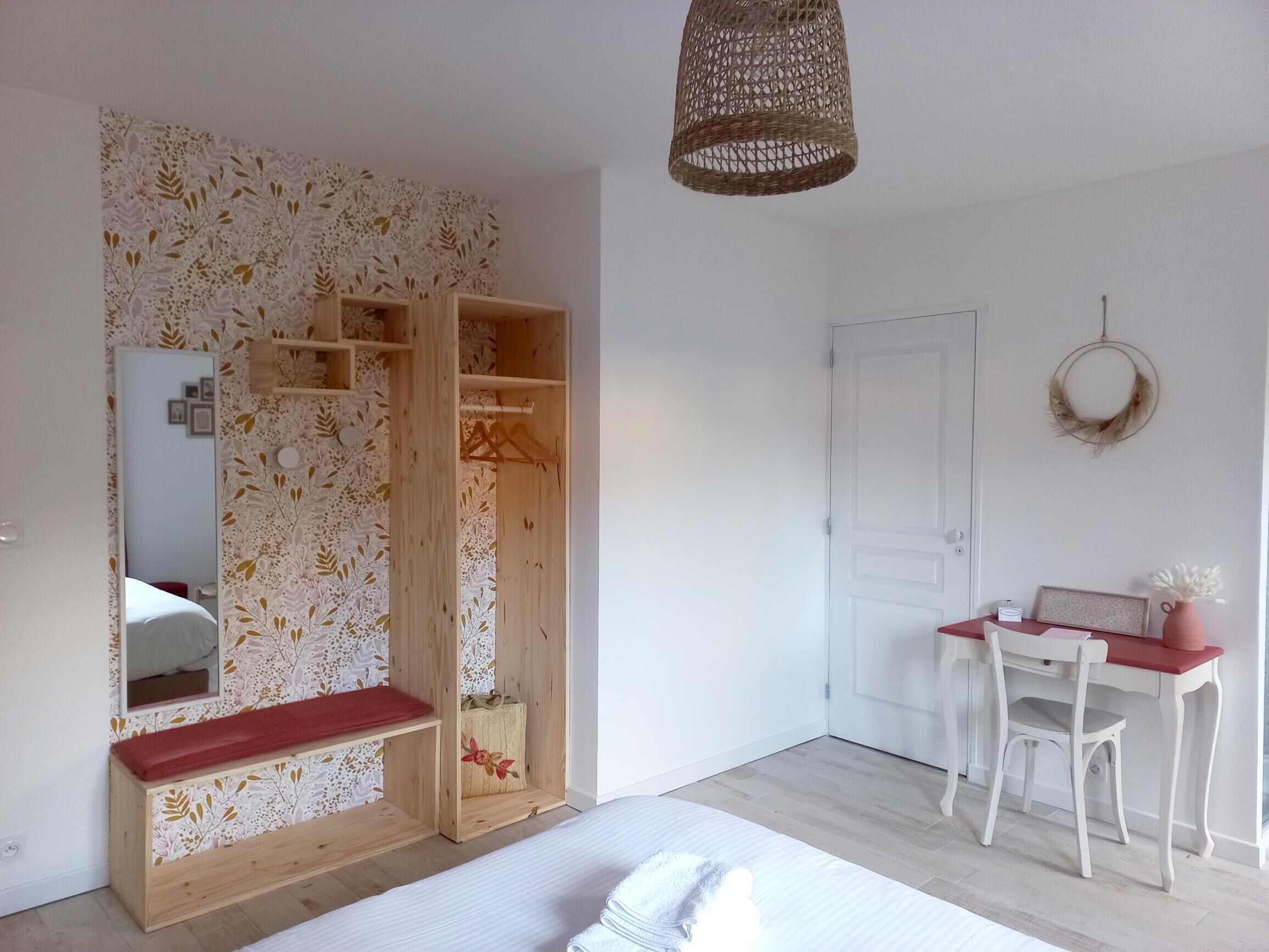 Un dormitorio con armario de madera, espejo, escritorio con silla y lámpara colgante.