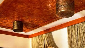 Ein Zimmer mit einer gestreiften Couch, einem dekorativen Teppich und einer Chandelier.