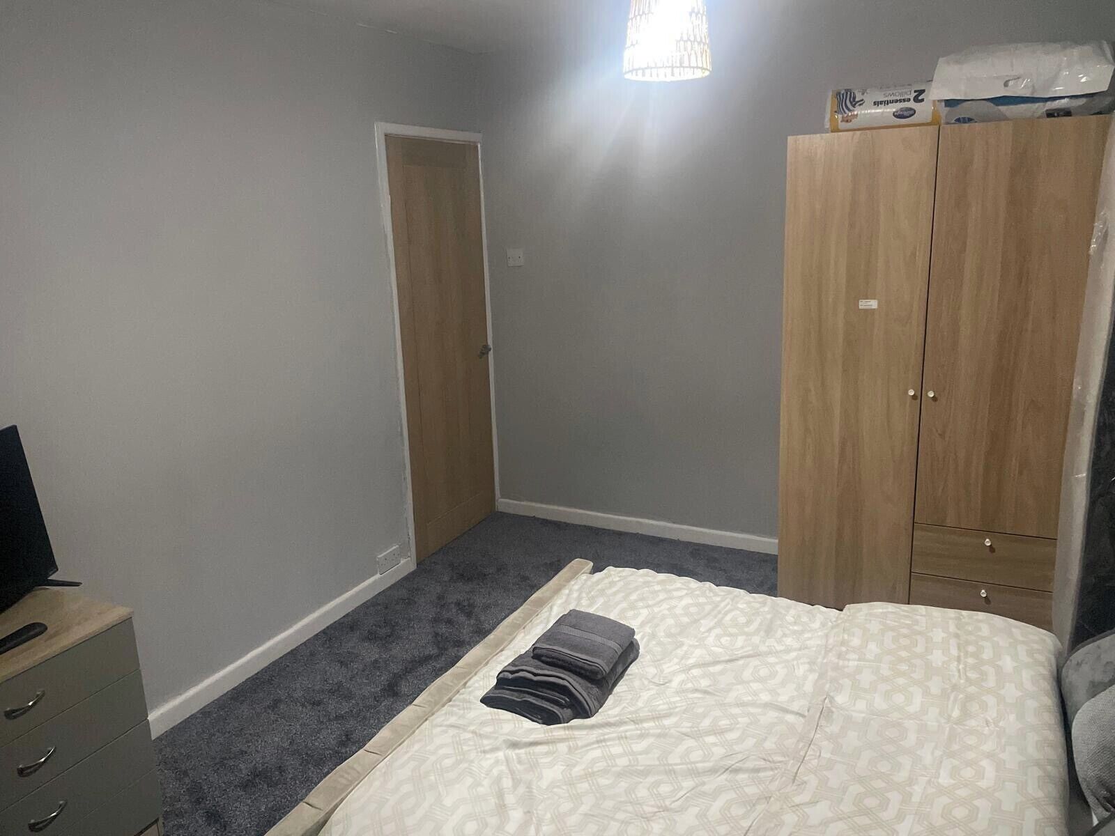 A bedroom with a bed, a wardrobe, a desk, and a door.