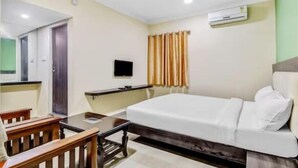 Una camera d'albergo con un letto, una scrivania, una sedia, un televisore e una finestra con tende.