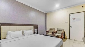 Una camera d'albergo con un letto grande, due comodini, una sedia e una porta.