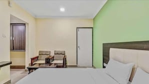 Una camera d'albergo con un letto, due poltrone, un tavolino e una porta.