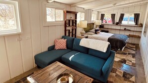 Ein geräumiges Wohnzimmer mit einem blauen Sofa, einem Holztisch und einem gemusterten Teppich.
