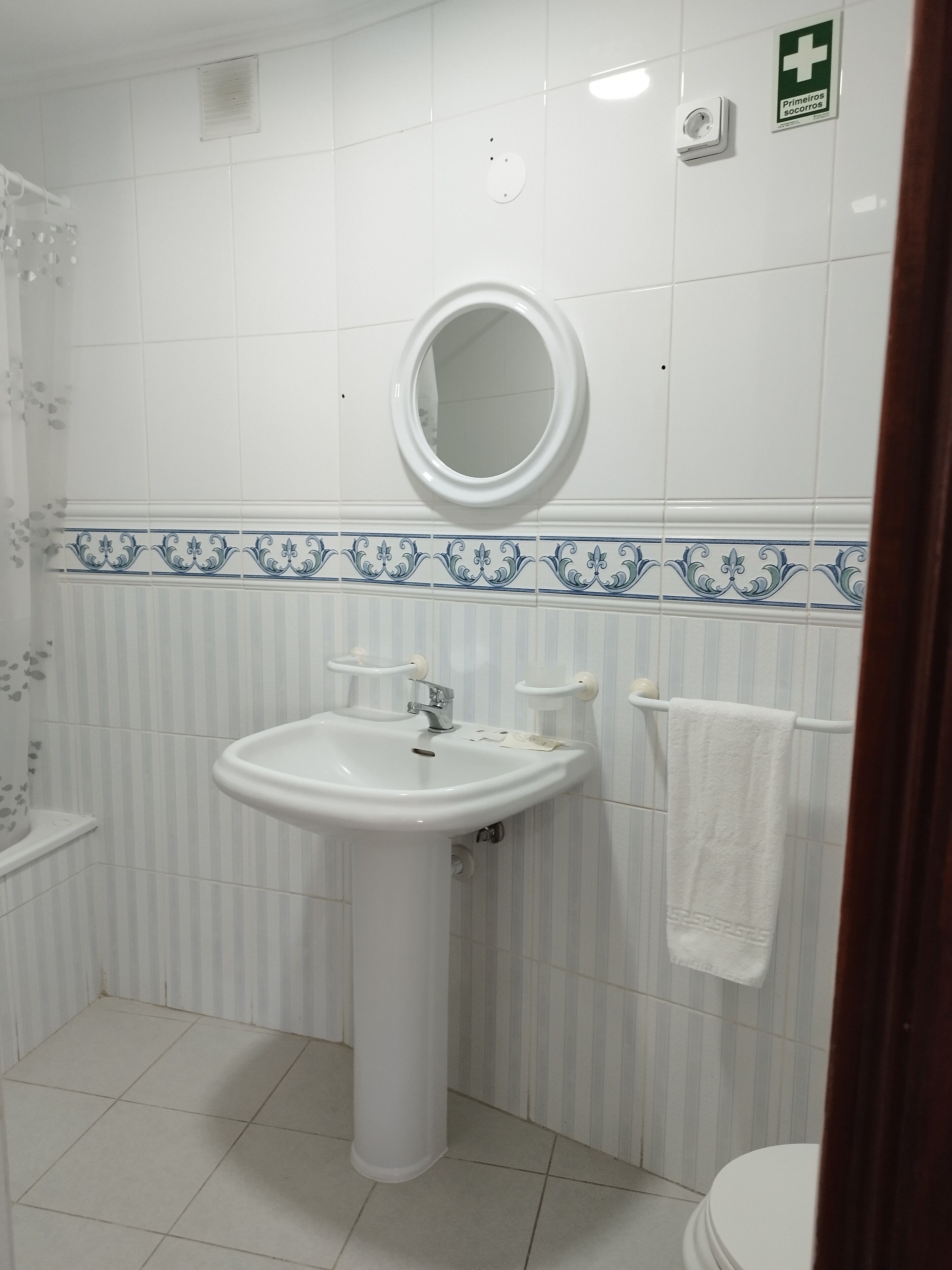 A bathroom with a white sink, a mirror, a towel rack, and a toilet.
