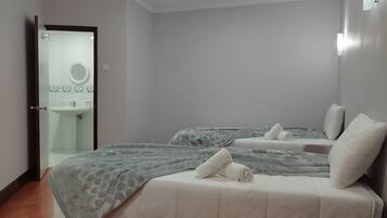 A bedroom with two beds, a bathroom with a sink, and a mirror.