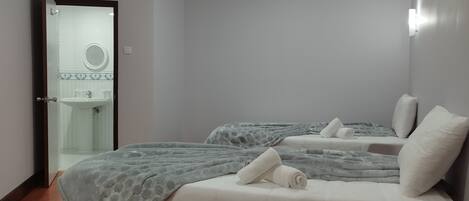 Un dormitorio con dos camas, un baño con lavamanos y un espejo.