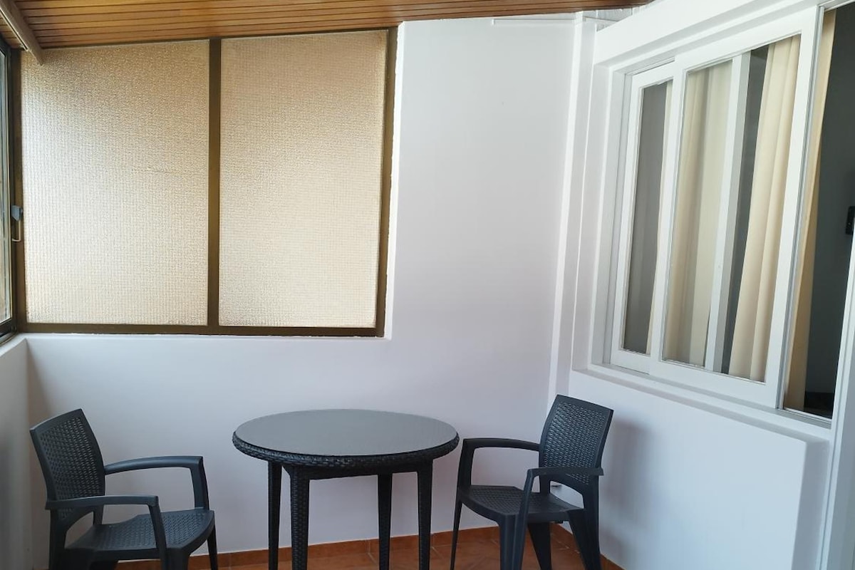 Egy csempézett padlós szoba, egy kerek asztallal és négy székkel.