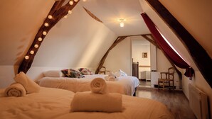 Un dormitorio estilo ático acogedor con dos camas, vigas de madera y luces colgantes.