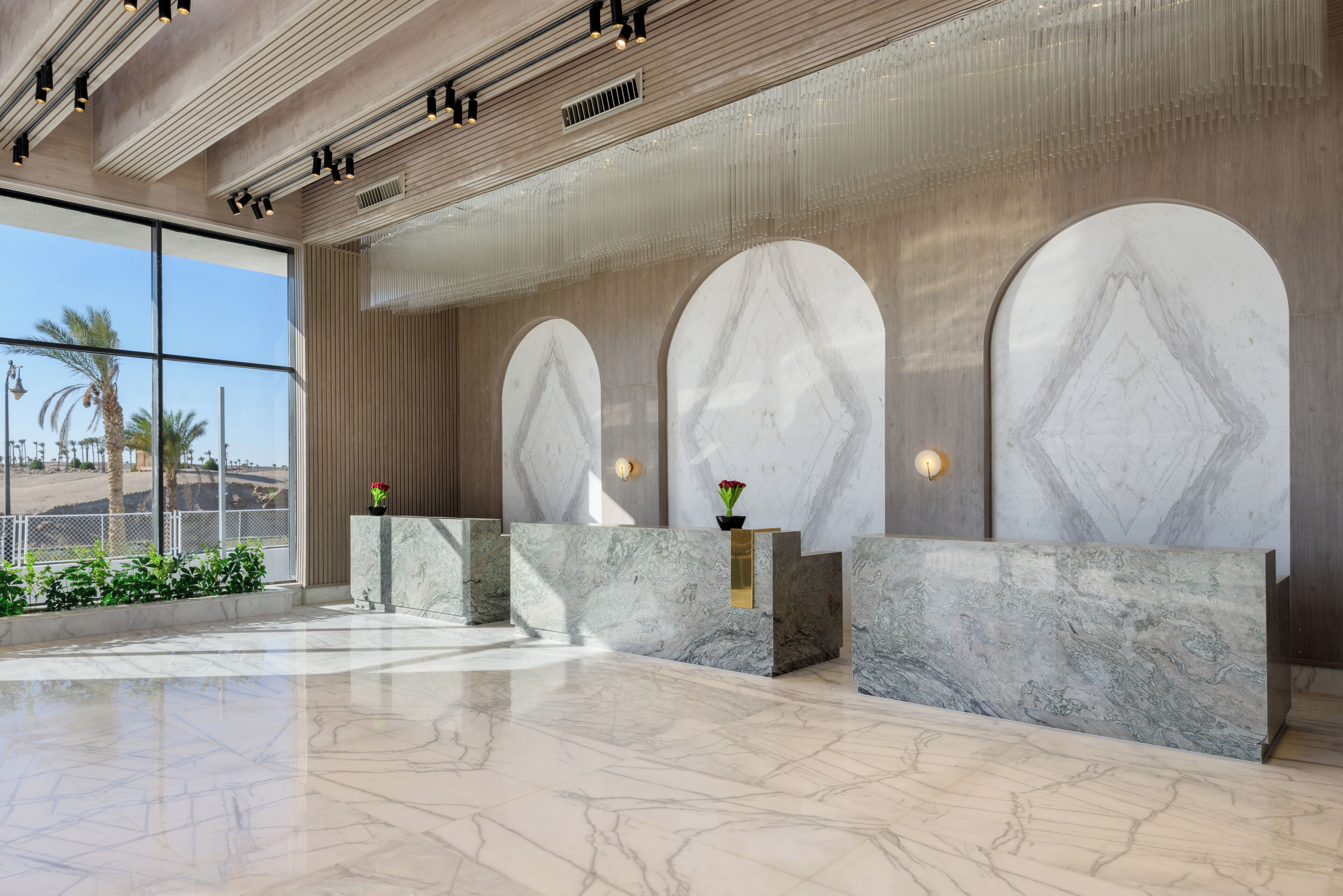 Un hall d’entrée doté de comptoirs de réception en marbre, de grandes fenêtres en arc de cercle et d’un design épuré et moderne.