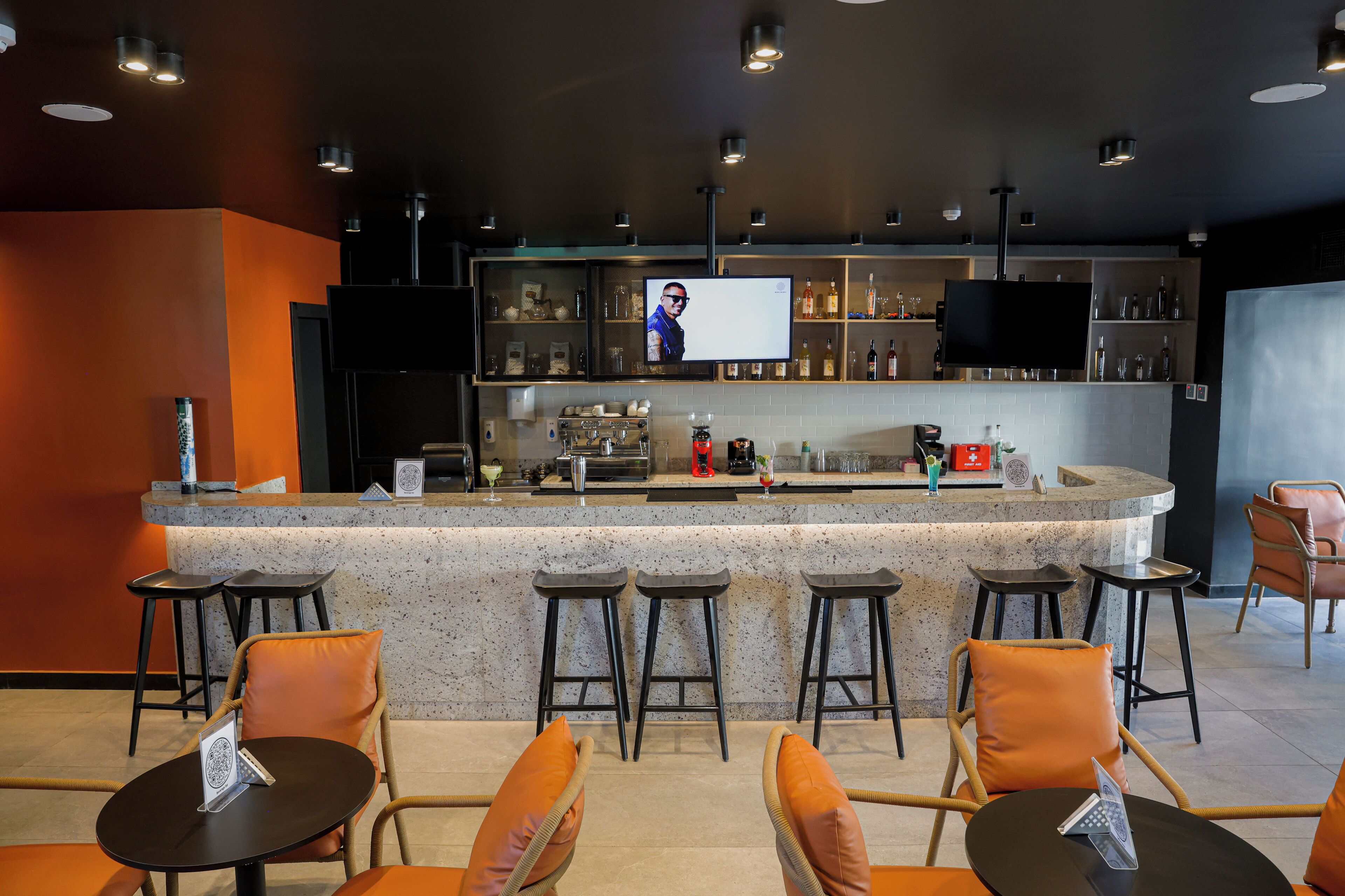 Zona de bar con mostrador, taburetes y una pantalla de televisión.