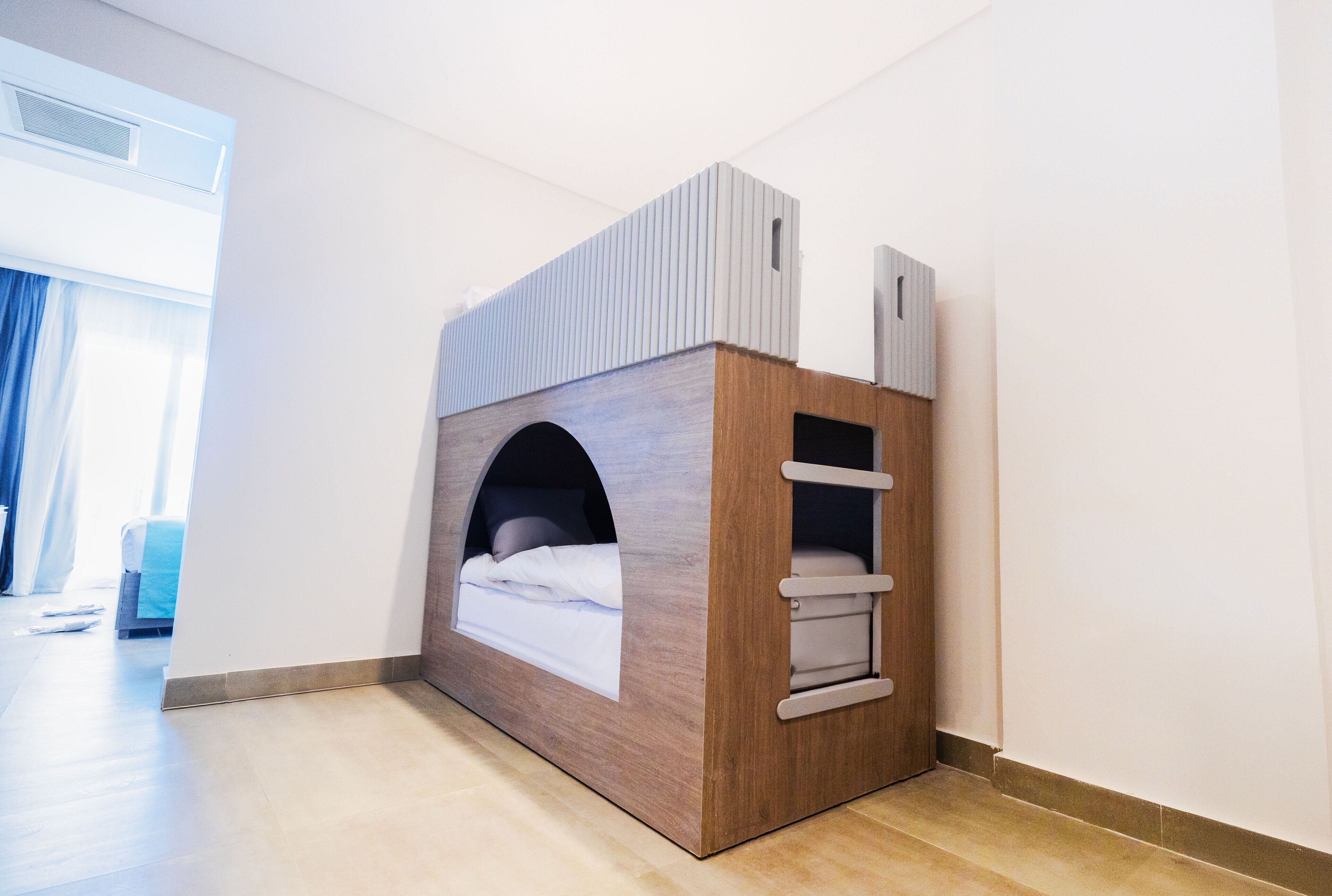 A modern, compact room with a built-in bed, a small window, and a door.