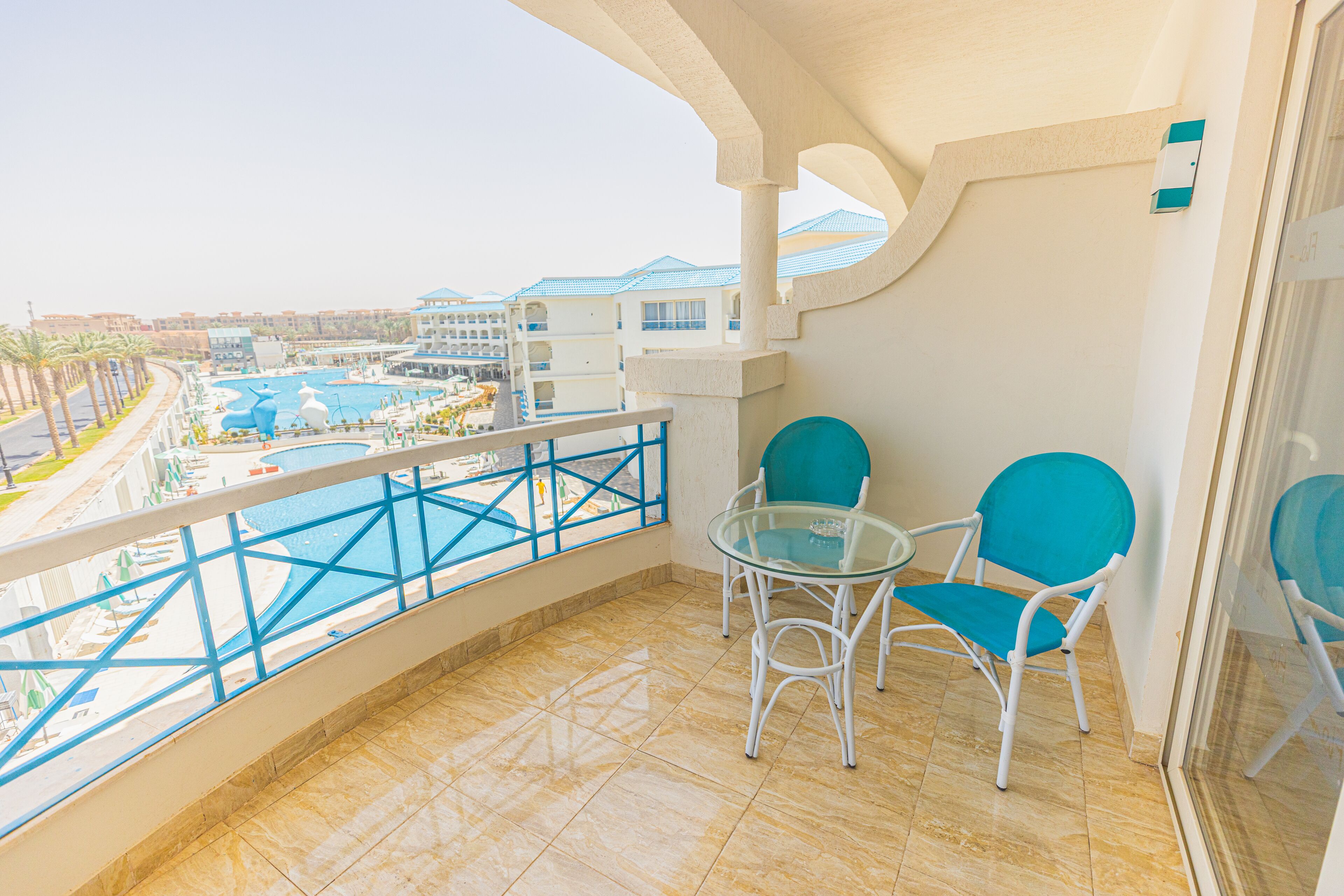 A balcony with a view of a pool and resort buildings.