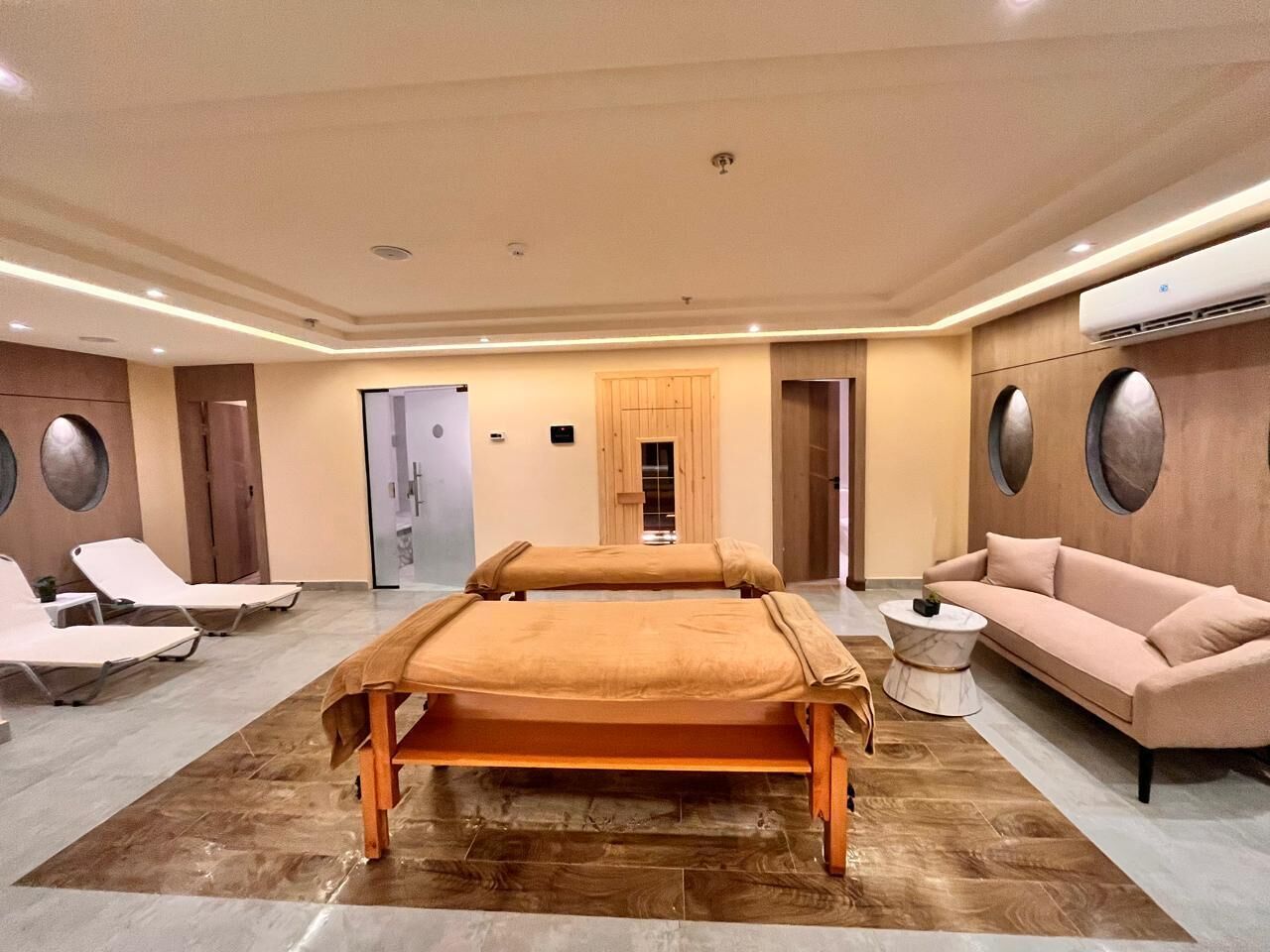 A spa room with two massage tables, a sofa, and a small round table.