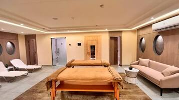 Un salón de spa con dos camillas de masaje, un sofá y una mesita redonda.