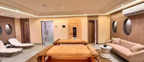 A spa room with two massage tables, a sofa, and a small round table.