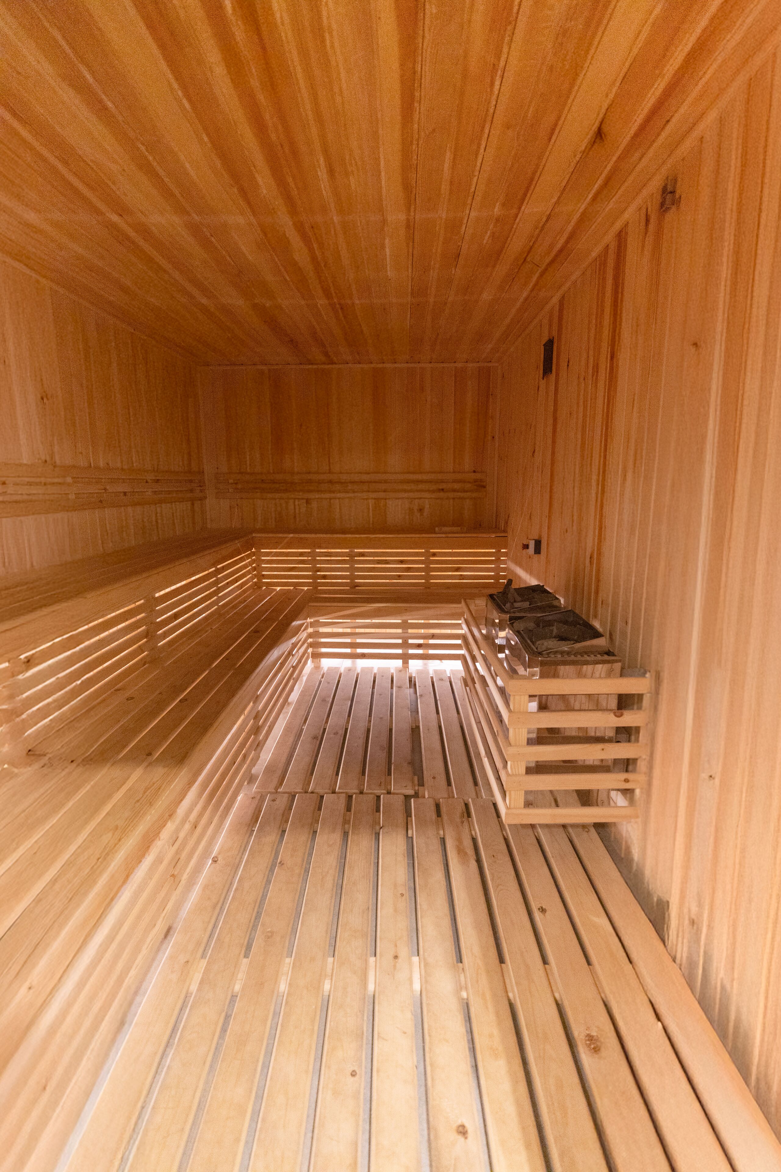 A sauna with wooden benches and a bench with a heater.