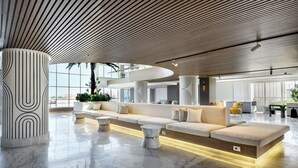 Una hall d'albergo moderna con un divano curvo, pavimento in marmo e soffitto in legno.