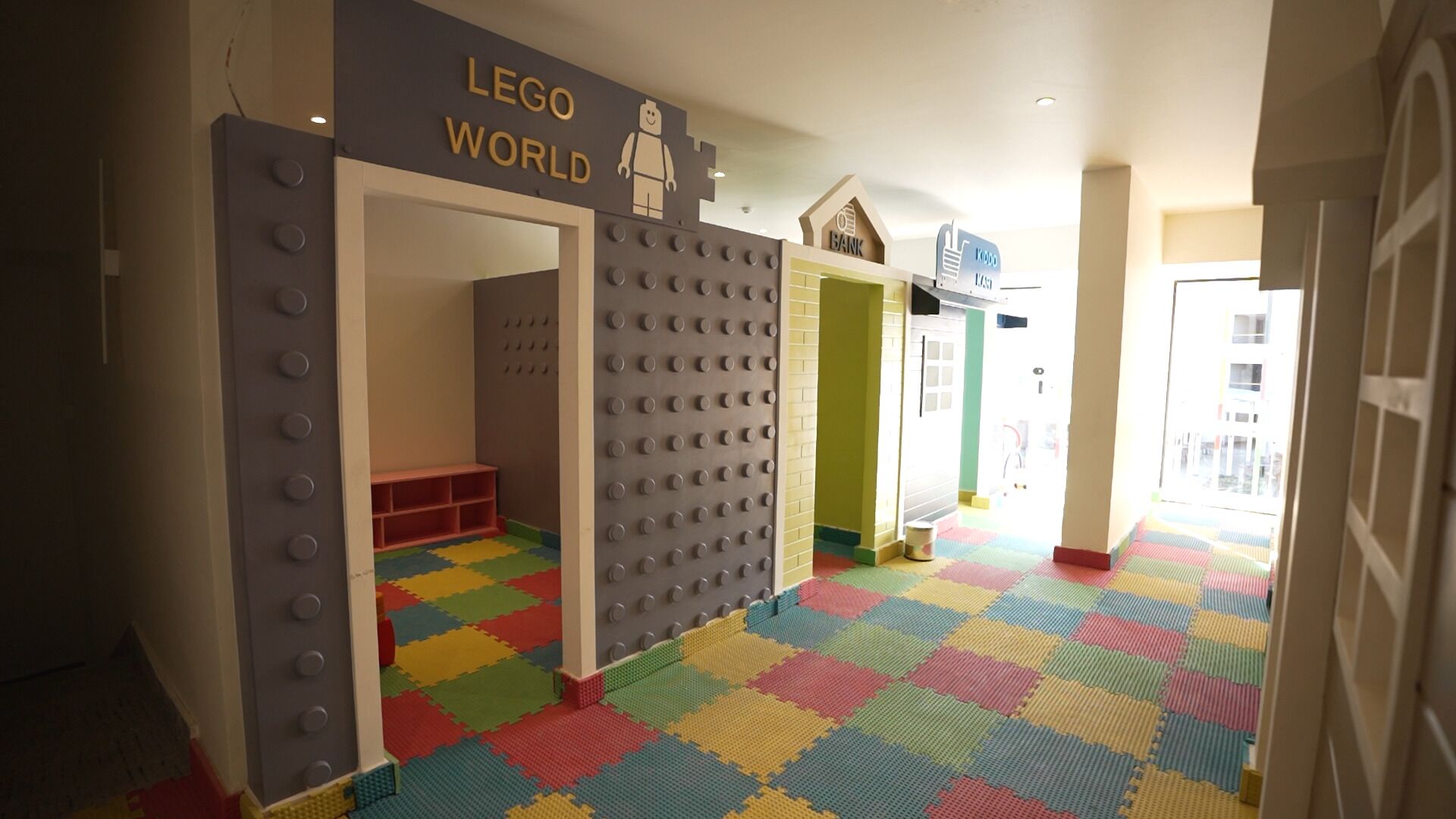 A LEGO-themed play area with a colorful floor and a sign reading "LEGO WORLD".