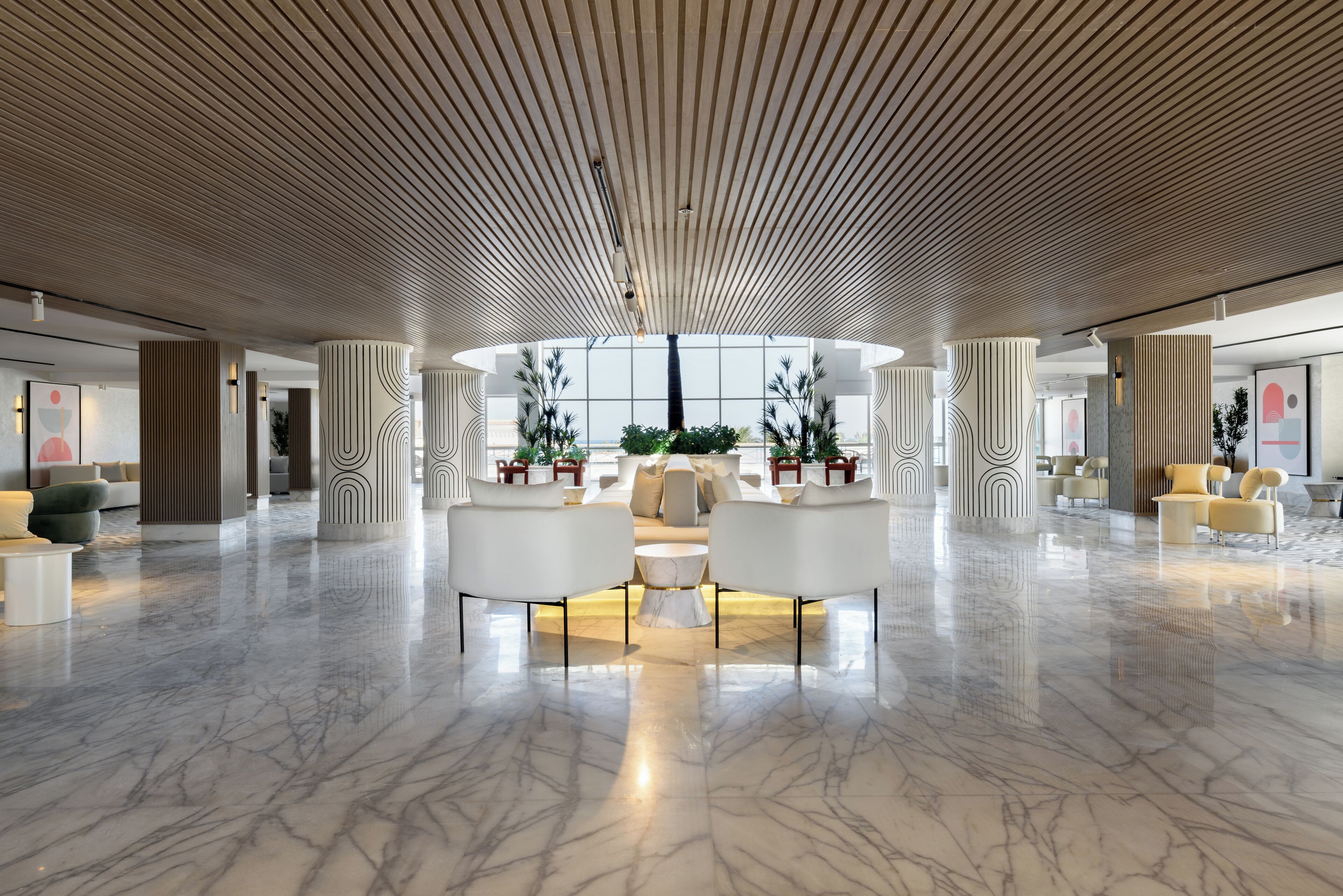 A spacious lobby with a high ceiling, marble flooring, and modern furniture.