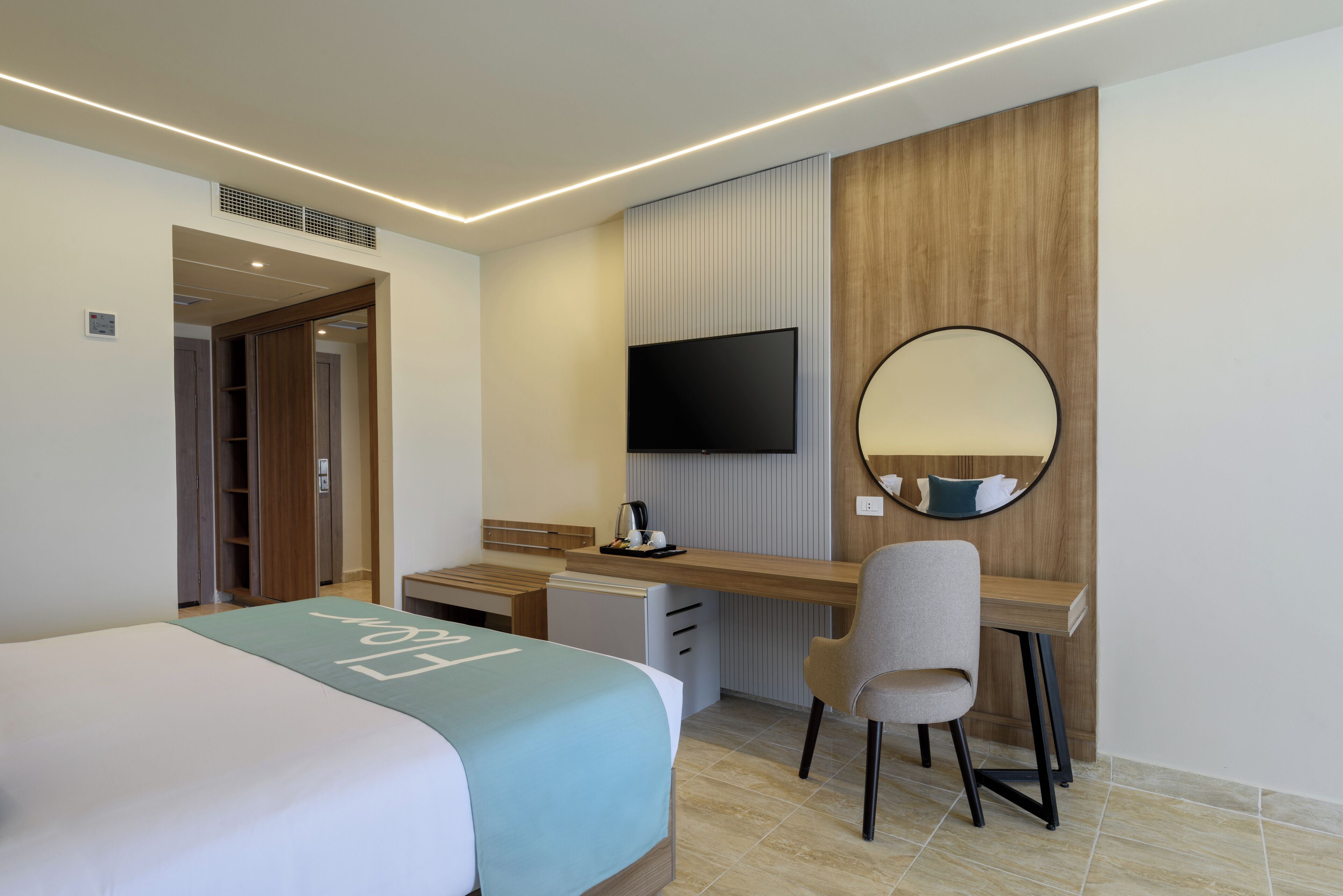 Une chambre d’hôtel avec un lit, un bureau, une chaise, une télévision et un miroir.