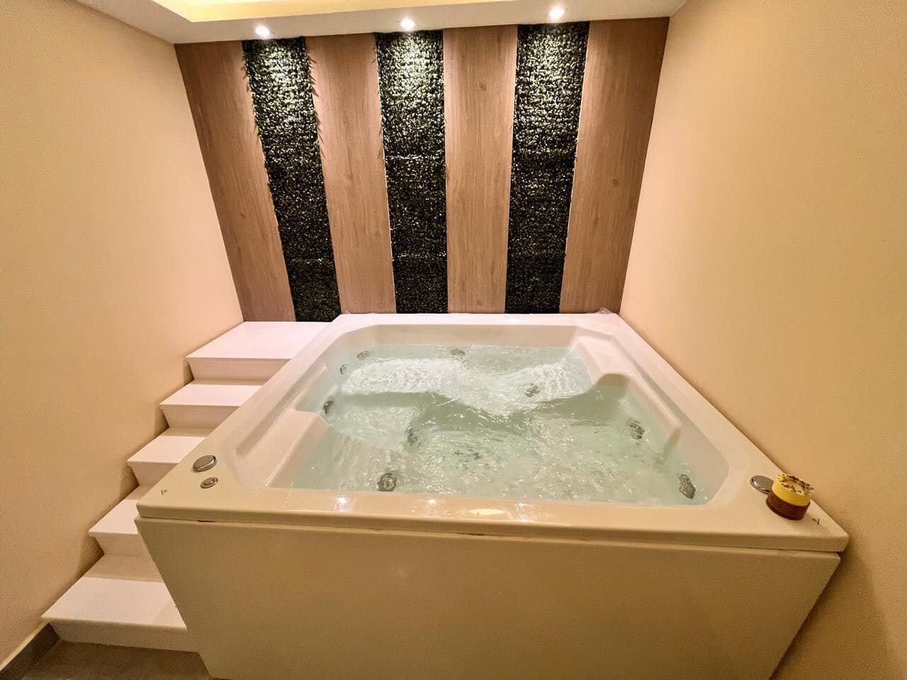A spa room with a hot tub, wooden panel wall, and a small decorative item on the tub.