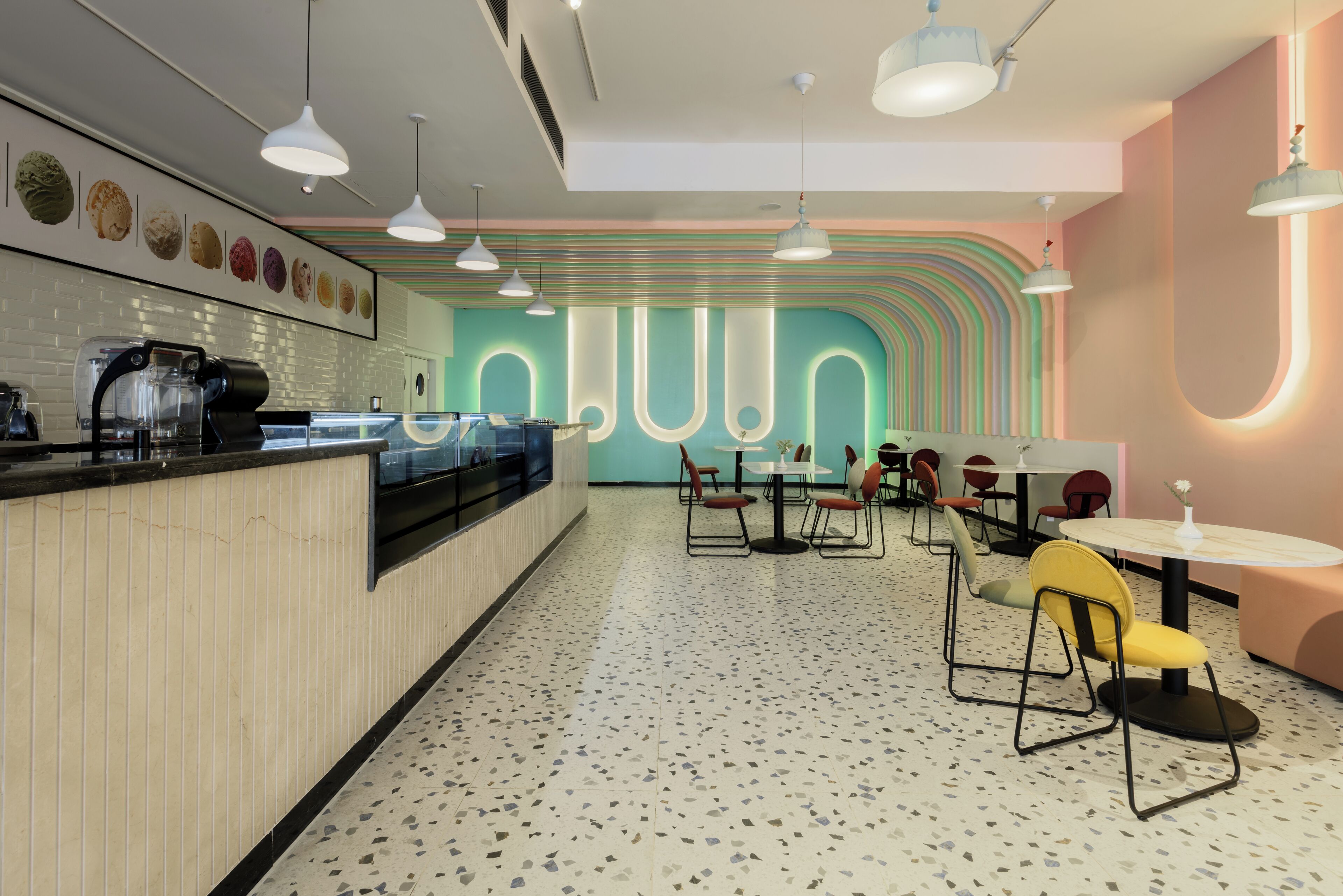 A modern cafe interior with a counter, seating area, and a wall with a unique design.
