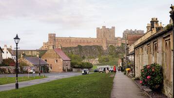 A historic town with a prominent castle in the background, narrow streets, and traditional stone buildings.