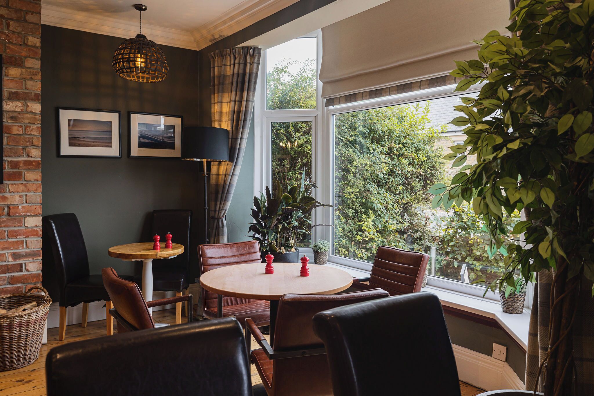 A cozy dining area with a round table, leather chairs, and a view of greenery outside.