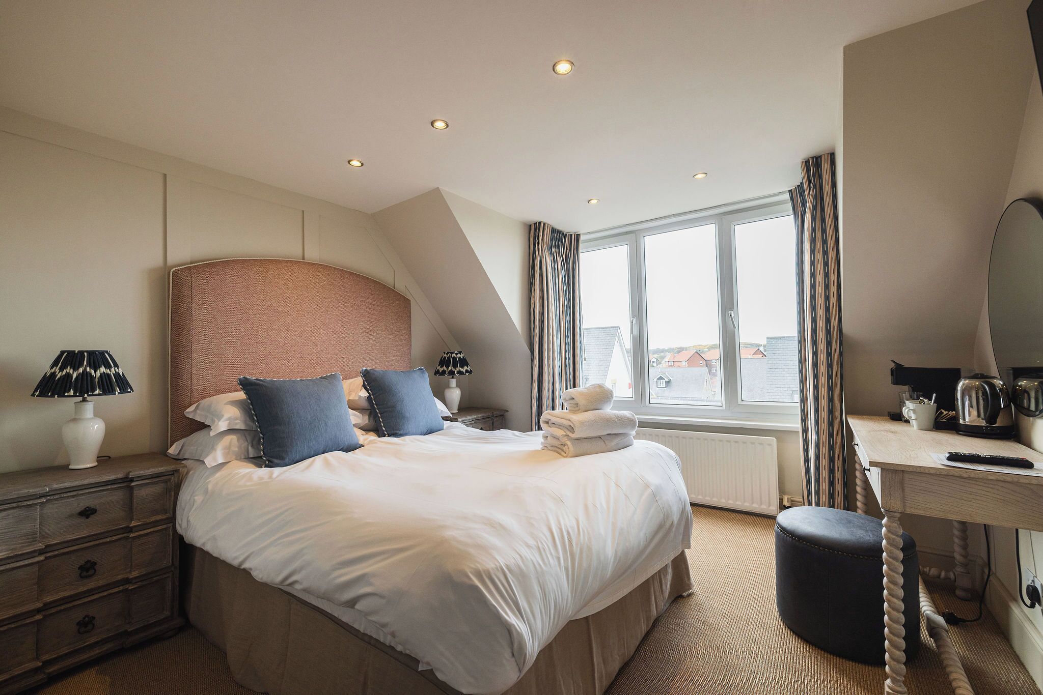 A hotel room with a large bed, bedside lamps, a desk, and a view of the outside.