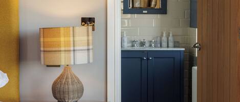 A bedroom with a bed, a bedside table with a lamp, a dresser, and a mirror.