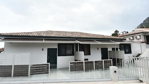 A modern building with a tiled roof, white exterior walls, and a gated entrance. - CORFU GOLD LUXURY SUITES (Corfu)