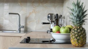 A kitchen with a marble backsplash, a coffee machine, a bowl of fruit, and a pineapple. - CORFU GOLD LUXURY SUITES (Corfu)
