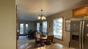 A kitchen with granite countertops, a stainless steel refrigerator, and a dining area with a wooden table and chairs. - Island Dreaming Retreat 3 Bedroom Cottage (Frisco)