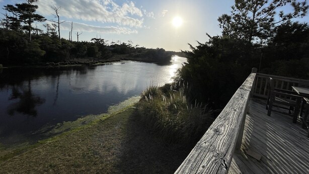 A wooden deck overlooking a calm river with trees and a clear sky. - Island Dreaming Retreat 3 Bedroom Cottage (Frisco)