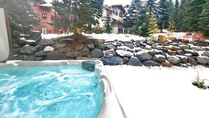 Un jacuzzi con vistas a un paisaje nevado y un muro de piedra.