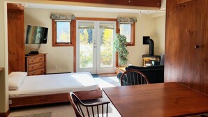 Une chambre à coucher comprenant un lit, une commode en bois, une télévision et un coin repas avec une table et une chaise.
