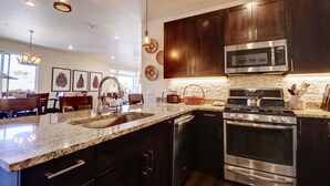 A modern kitchen with dark wood cabinets, stainless steel appliances, and a granite countertop. - Sail Lofts 101 2 Bedroom Condo (Dillon)