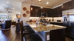 A modern kitchen with dark cabinets, stainless steel appliances, and a granite countertop. - Sail Lofts 101 2 Bedroom Condo (Dillon)