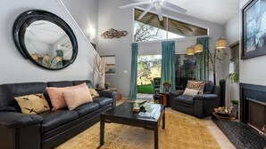 A modern living room with a black leather sofa, a glass coffee table, and a fireplace.