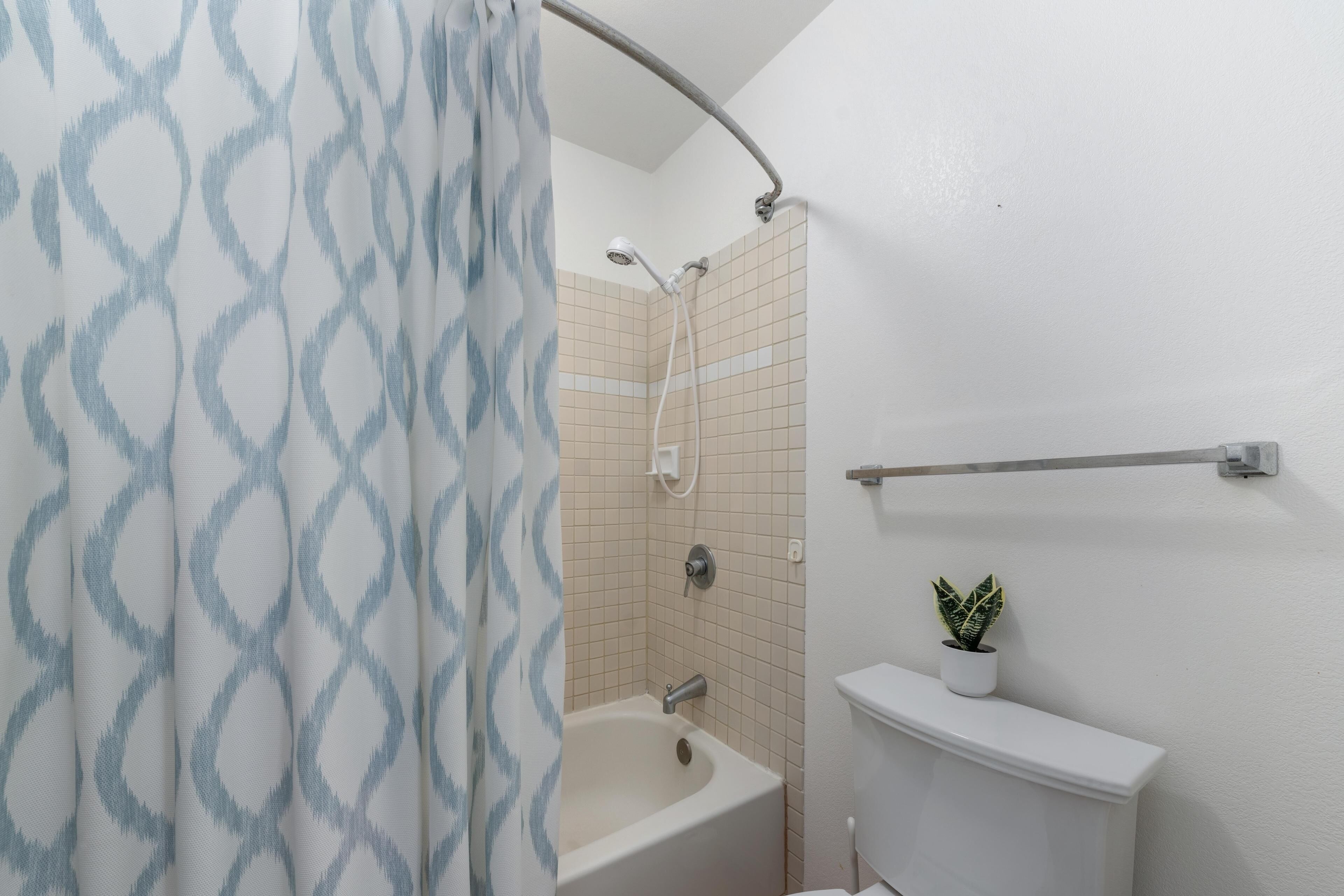 Une salle de bain équipée d’une douche, d’une baignoire et d’un lavabo, avec une plante en pot.