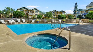 A swimming pool with a hot tub, lounge chairs, and a view of apartment buildings.