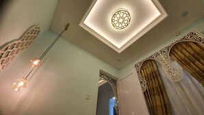 Ein Zimmer mit einer dekorativen Deckenleuchte, einer Wand mit Muster und einer Tür mit Vorhängen.