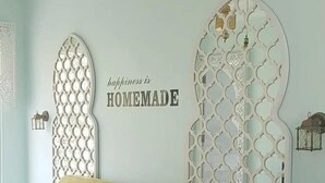 Ein Zimmer mit blauer Wand, einem beigen Sofa und Wandverkleidungen mit dem Schriftzug 'happiness is HOMEMADE'.