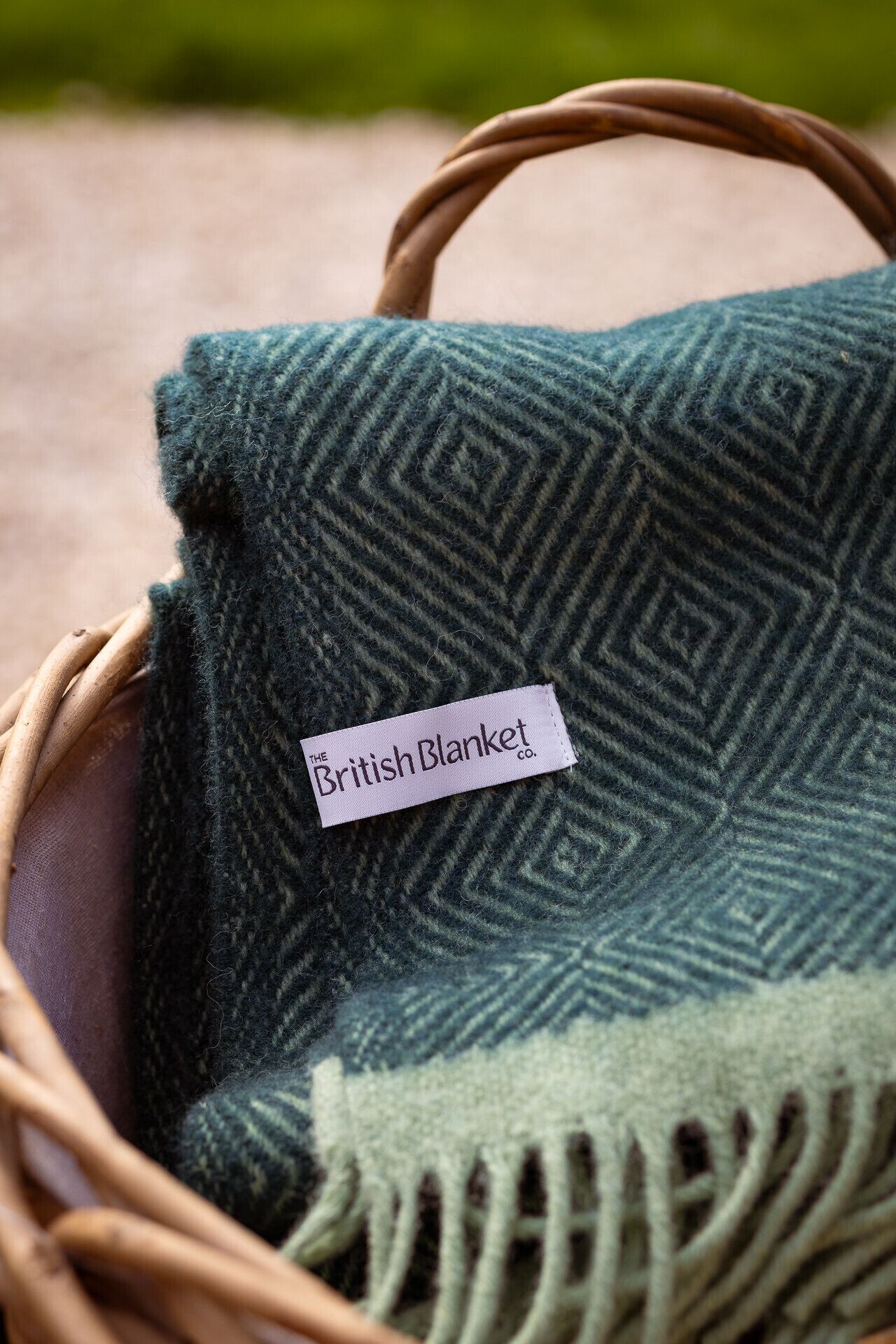 A woven blanket with a label inside a wicker basket.