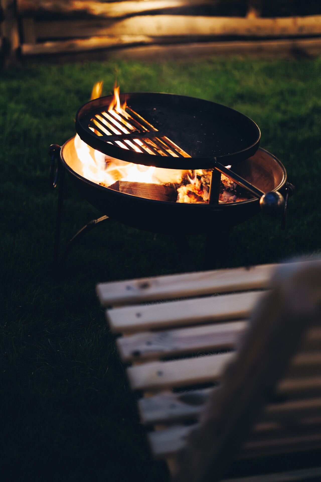 A campfire with a metal grill, surrounded by a grassy area.
