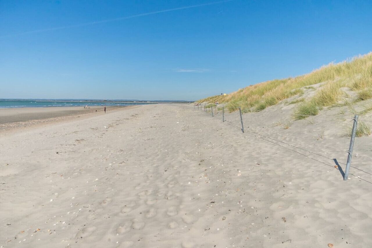Una platja sorrenca amb dunes i un cel serè.