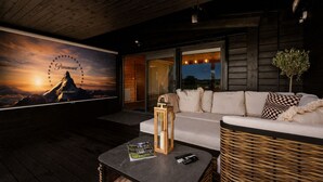 Ein modernes Interieur mit einer großen Wandmalerei, einer Couch, einem Korbstuhl und einem Tisch mit Zeitschriften.